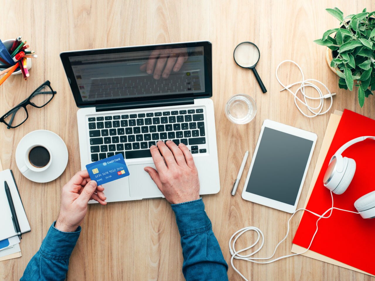 Man working at desk and purchasing products online, he is making a payment using a credit card, online shopping concept